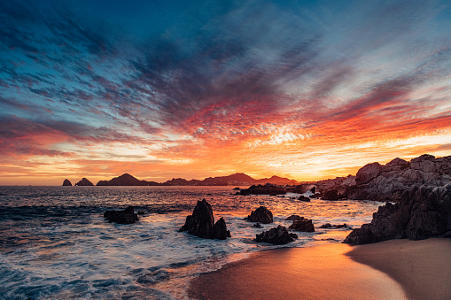 Dramatic sunset in Cabo San Lucas with the view of Lands End at the horizon, Mexico.