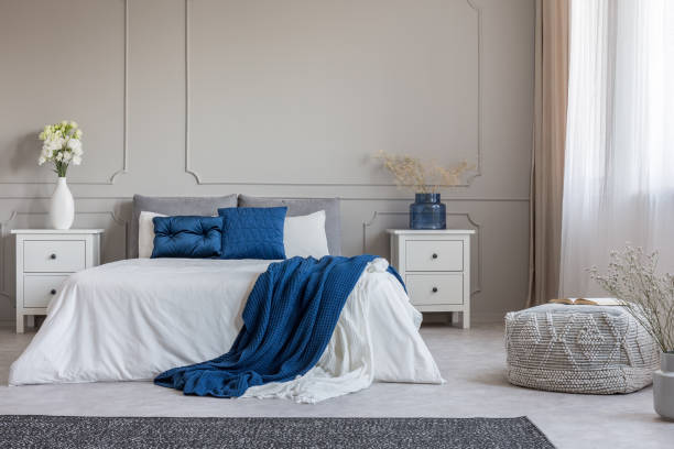 istock Copy space on empty grey wall of fashionable grey white and blue bedroom interior 1141278043
