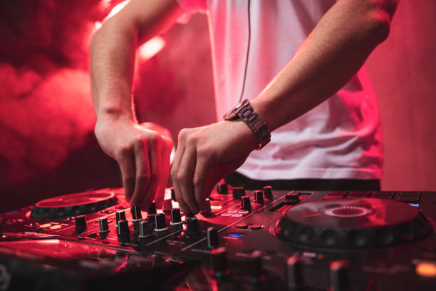 Dj mixing at party festival with red light and smoke in background. stock photo