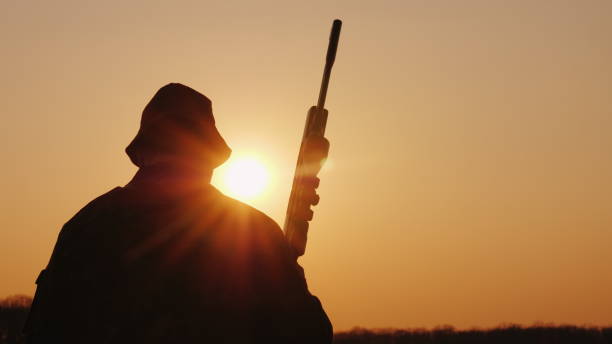 istock A hunter with a gun goes forward across the field towards the setting sun. Hobby for men 1141278260