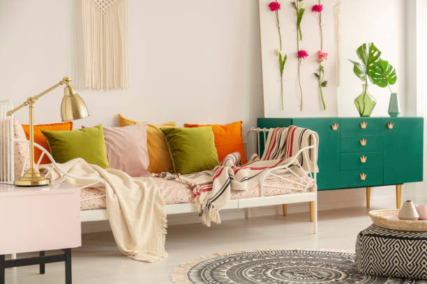 istock Olive green, pastel pink, yellow and orange pillows on single metal bed with patterned bedding in boho bedroom interior for girl 1141283262
