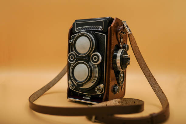 hermosa cámara de tamaño mediano a la antigua dentro de la caja de cuero sobre un fondo anaranjado. cámara de estilo retro de diseño antiguo. la tecnología antigua - single lense reflex fotografías e imágenes de stock