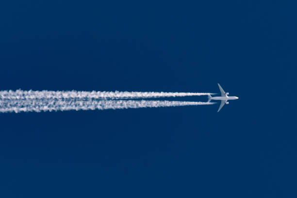 avion vole laissant la trace contrail sur un ciel bleu clair et haut. - pulse trace photos et images de collection