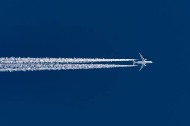 Airplane flies leaving contrail trace on a clear high blue sky. Airplane flies leaving contrail trace on a clear high blue sky jet exhaust stock pictures, royalty-free photos & images