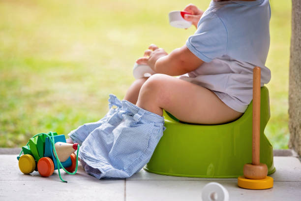 Sweet toddler boy, sitting on potty on a back porch in a holiday resort patio Sweet toddler boy, sitting on potty on a back porch in a holiday resort patio, playing with toys potty toilet child bathroom stock pictures, royalty-free photos & images