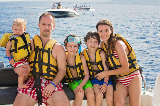 famiglia felice con giubbotti di salvataggio, divertirsi durante una gita in barca mentre è in vacanza - sailing nautical vessel family lake foto e immagini stock