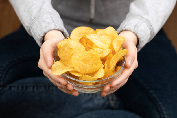 istock Female hand giving crispy potato chips bowl 1141285975