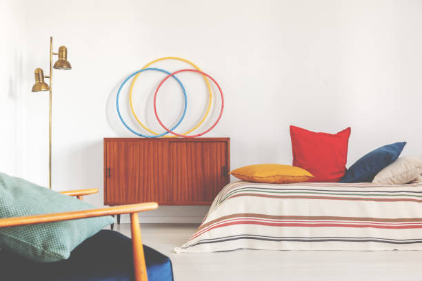 istock Hula hoops on a cupboard next to a bed with colorful pillows in a retro bedroom interior 1141290843