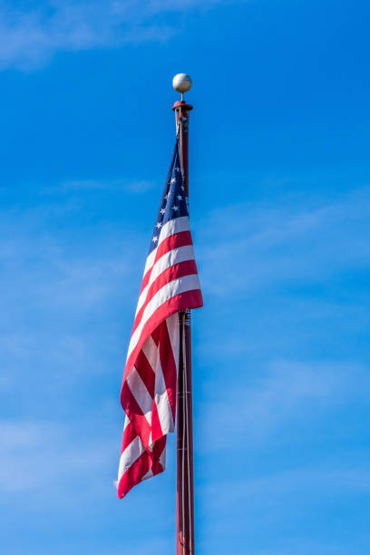 American flag hanging on flagpole against blue sky on a clear day