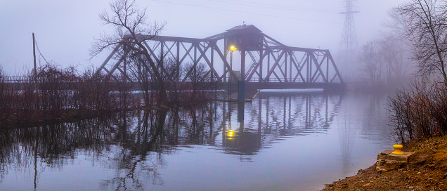 Eerie old railroad trestle bridge in foggy twilight.