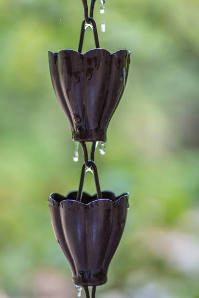 Closeup of metal rain chain with water droplets - water conservation