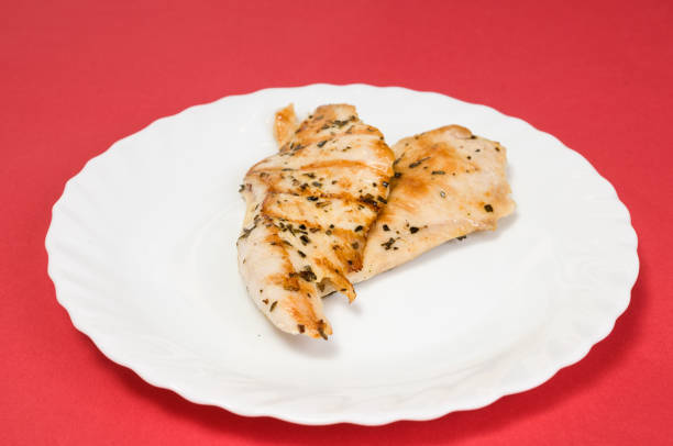 grilled chicken fillet on a white plate and red background