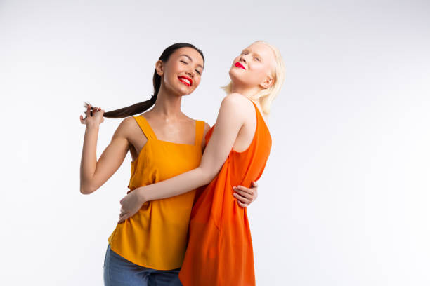 istock Women with red lips hugging while posing near white background 1141299440