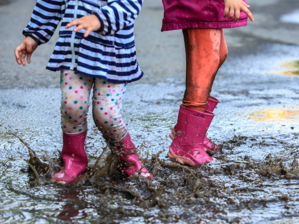 istock Playful child outdoor jump into puddle in boot after rain 1141299701