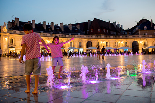 Children, refreshing on a very hot summer day, walking in fountain, playing with water at night, summertime