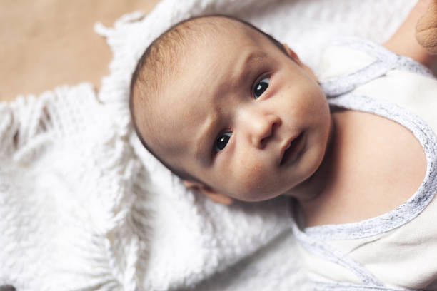 2 month baby boy lying. Close-up of adorable cute newborn baby boy of two months. Baby with suspicious face. Serious little kid. Emotional development in children. stock photo