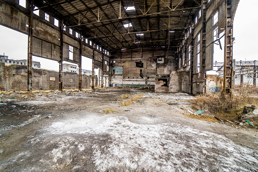 Damaged factory inside with many holes and ruined roof. Old factory background building after earthquake disaster or war.