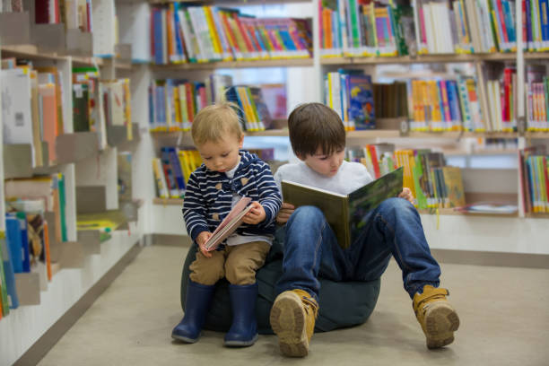 istock Smart toddler boy, educating himself in a library, reading books 1141301689