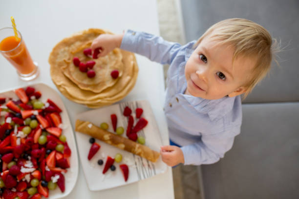 kleinkind, junge, essen pfannkuchen mit viel obst und saft - eierkuchen speise stock-fotos und bilder