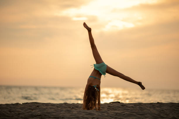 девушка, практикующая стойку на пляже - the splits фотографии стоковые фото и изображения