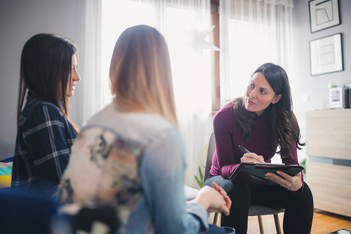 Pregnant counselor advising young lesbian couple at their home