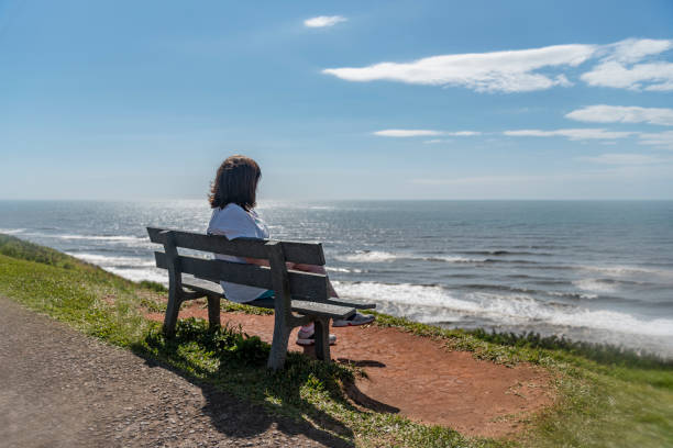 Woman sitting on bench in front of the sea, resting, thinking about the future and looking calmly forward