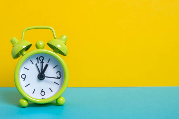 istock black vintage alarm clock on yellow color background 1141306554