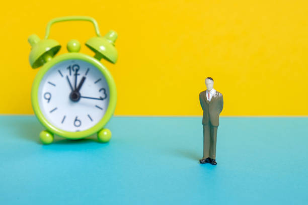 istock Man dummy next to a green vintage clock on a yellow background. 1141306565