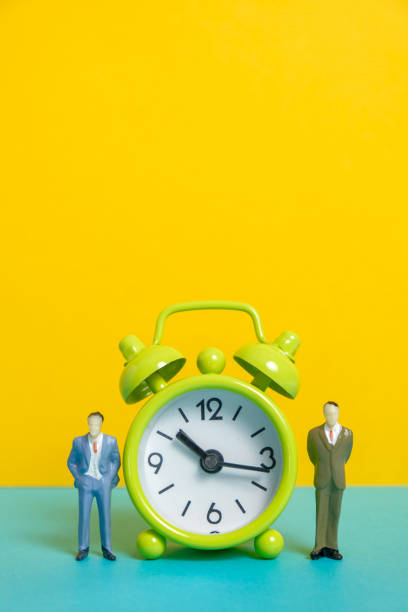istock Man's dummy next to a green vintage clock on a yellow background. 1141306611