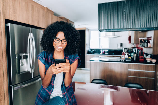 istock Young afro descendant teenager using smartphone at the kitchen 1141306875