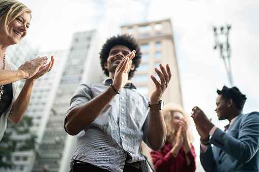 Business team celebrating success applauding outdoors