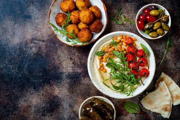 Homemade hummus with roasted cherry tomatoes and pita bread. Middle Eastern traditional and authentic arab cuisine. Top view, flat lay, overhead Arabic traditional cuisine. Middle Eastern meze with pita, olives, hummus, stuffed dolma, falafel balls, pickles. Mediterranean appetizer party idea meze stock pictures, royalty-free photos & images