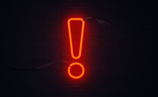 Exclamation point shaped red neon light on black wall. Horizontal composition with copy space. Alertness concept.