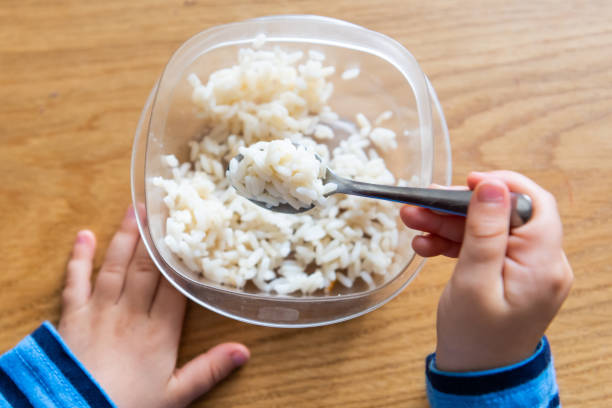 child hand holding a fork, he is having rice child hand holding a fork, he is having rice, from above preschooler caucasian one person part of stock pictures, royalty-free photos & images