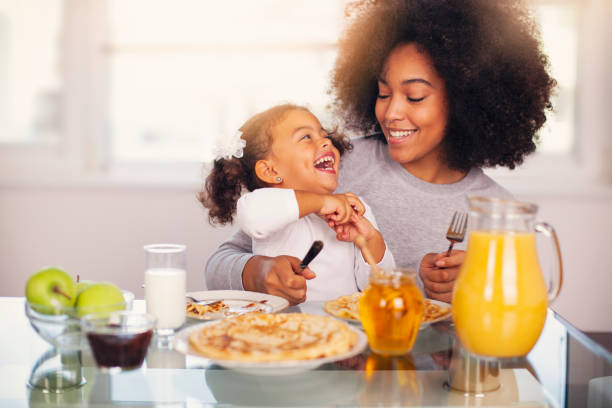 African-American young mother and daughter having breakfast