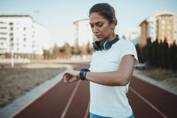 atleta femenina midiendo el tiempo mientras se ejecuta - running track women running spring fotografías e imágenes de stock