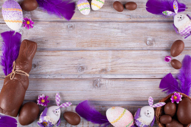 composición de pascua con huevos de chocolate y conejito en mesa rústica de madera. - easter flower purple frame fotografías e imágenes de stock