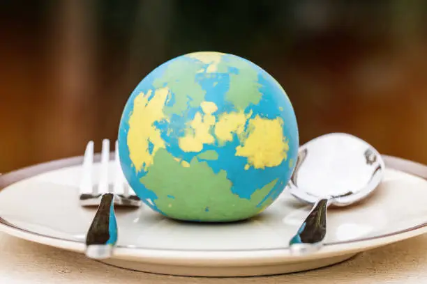 Globe model placed on plate with fork spoon for serve menu in famous hotels. International cuisine is practiced around the world often associated with specific region country. World food inter concept