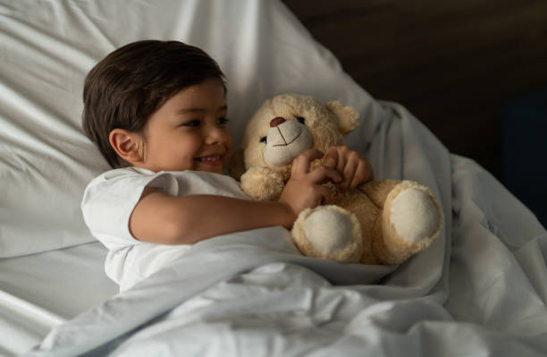 istock Beautiful little boy hugging his teddy bear while lying down on hospital bed 1141330662