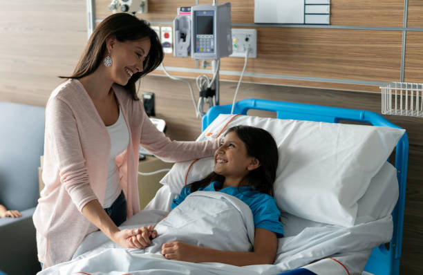istock Sweet mother caressing her daughters head while she is lying on hospital bed both smiling 1141330696