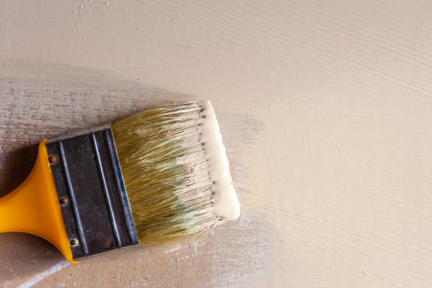 istock paint brush in beige paint on painted drywall, copy space 1141330848