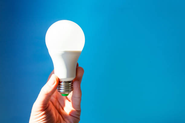 istock bright white LED light bulb in hand on blue background, copy space 1141330884