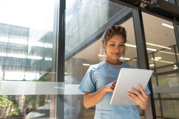Friendly young nurse looking at a medical chart on tablet slightly smiling