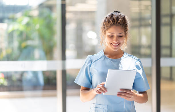 istock Beautiful young nurse at the hospital looking at something on tablet while smiling 1141333745