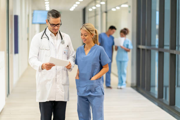istock Beautiful nurse paying attention to male doctor while he shows something on a document both smiling 1141333757