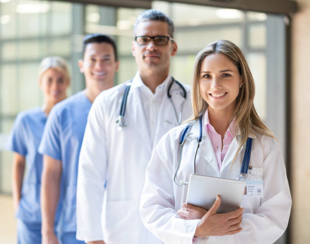 hermosa doctora latinoamericana que lidera a su equipo en el hospital sonriendo a la cámara - men latin american and hispanic ethnicity young men smiling fotografías e imágenes de stock