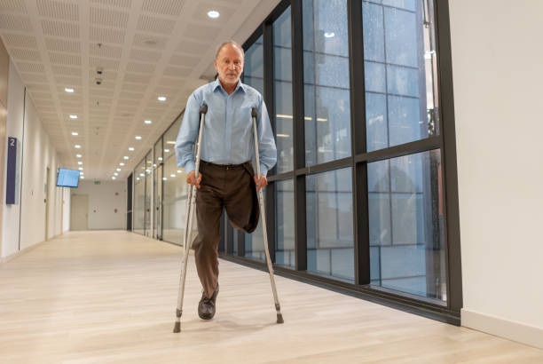 istock Senior amputee man walking through the hospital's corridor using crutches 1141333812