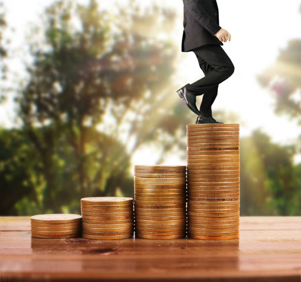 istock Businessman walk on stack of coins which grows success 1141335355