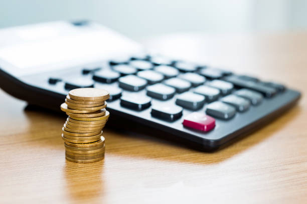 Calculator and coins on wooden table.