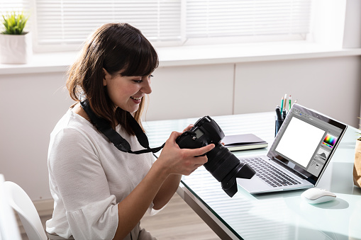 Close-up Of An Editor Looking At Photograph In DSLR Camera At Workplace